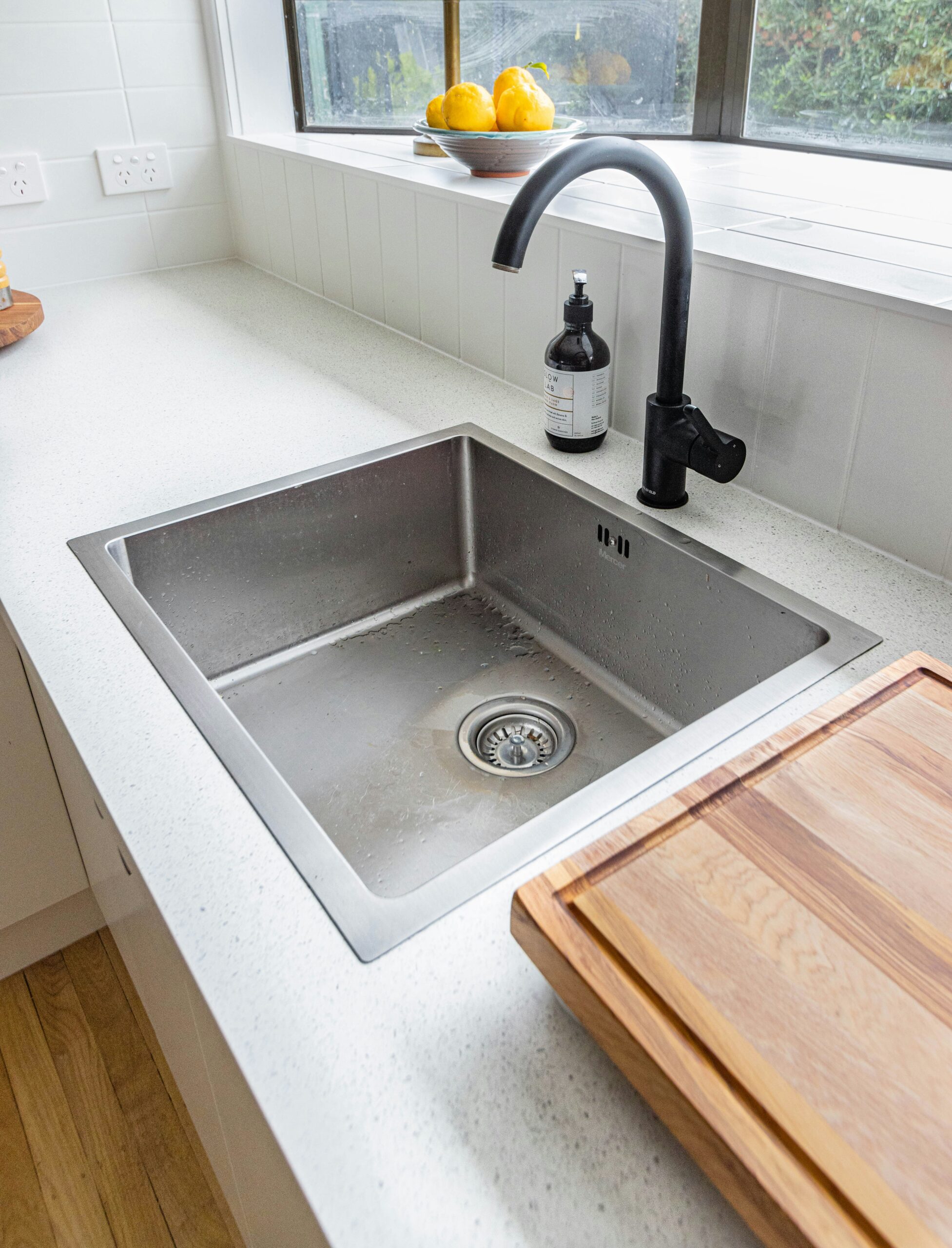 Under-sink view of a newly installed garbage disposal with water dripping from connections.
